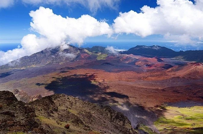 The Haleakala crater in daylight with cloud shadows across red and grey cinder slopes
